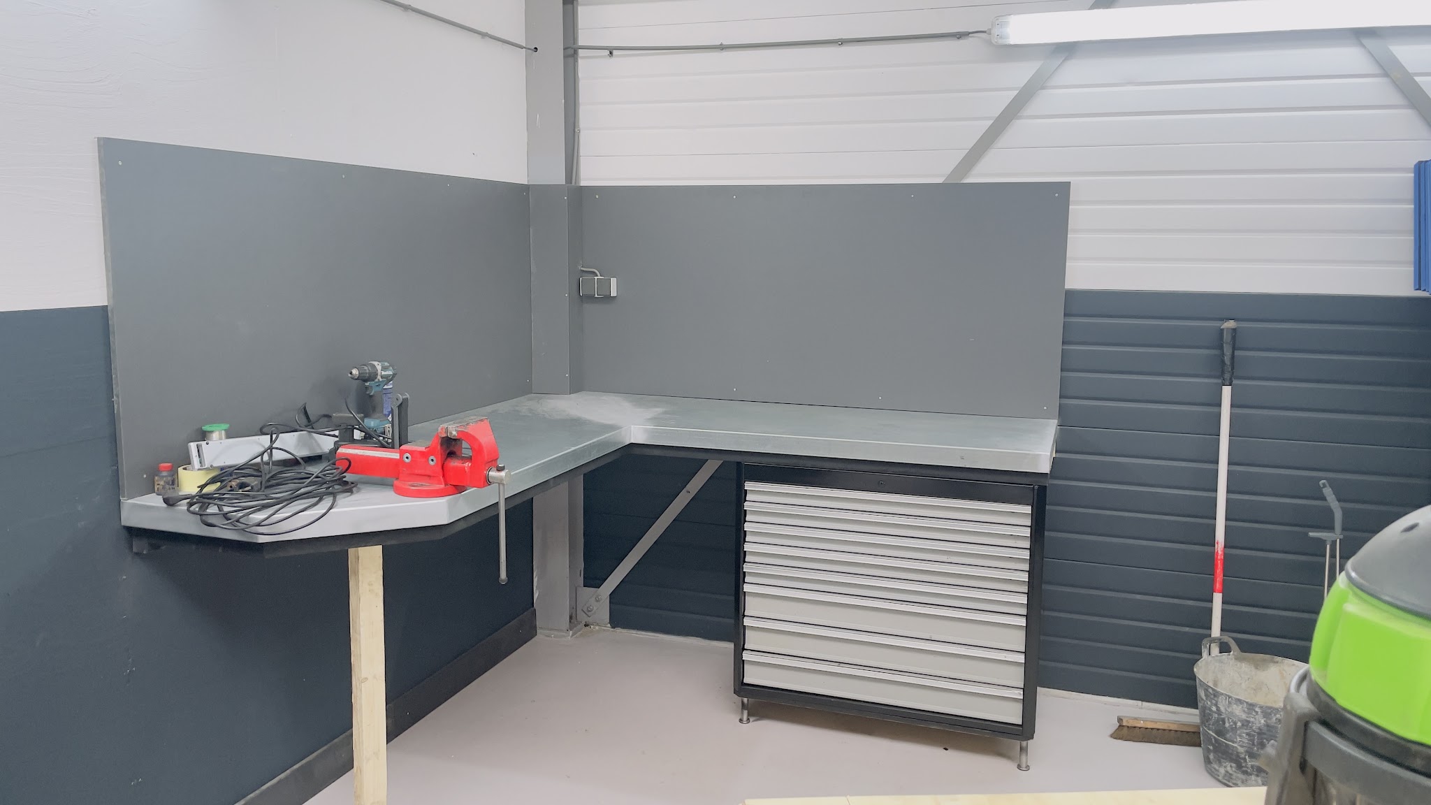 Een werkbank met bankschroef en een ladekast in de hoek van de werkplaats